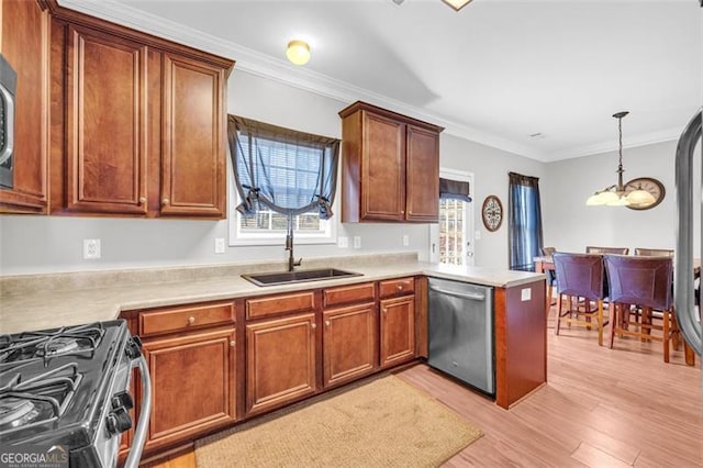 kitchen featuring a peninsula, a sink, light countertops, appliances with stainless steel finishes, and decorative light fixtures