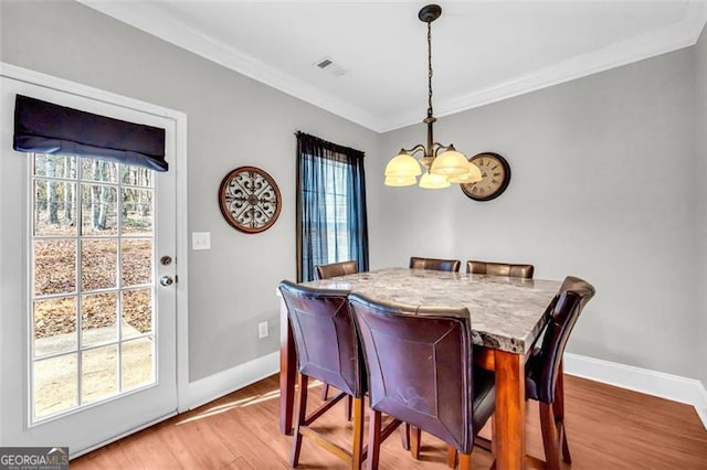 dining space with baseboards, visible vents, crown molding, and wood finished floors