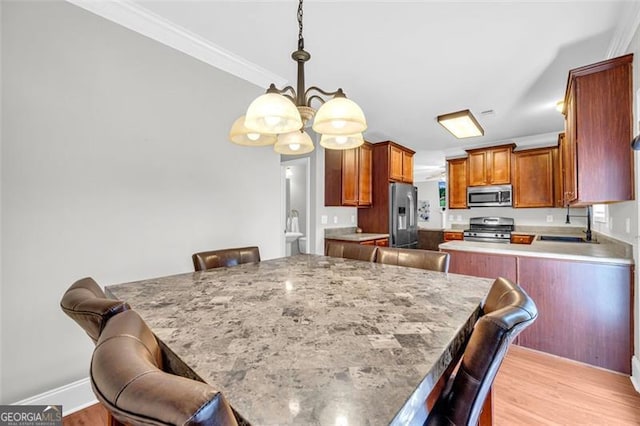 kitchen with stainless steel appliances, light countertops, brown cabinets, a kitchen bar, and pendant lighting