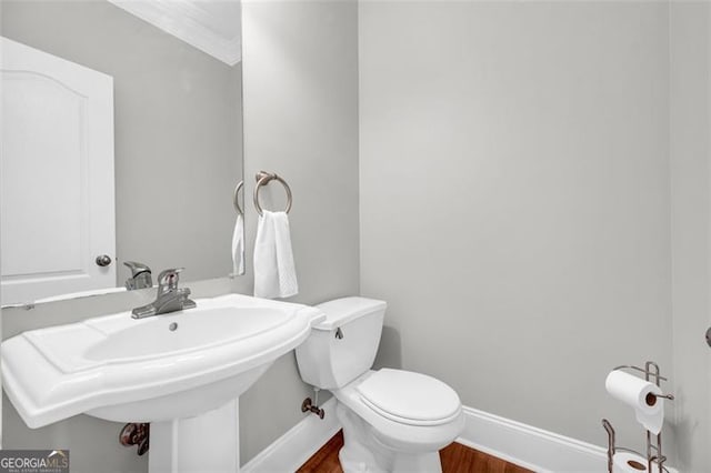 bathroom with toilet, a sink, baseboards, and wood finished floors