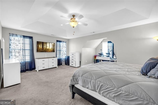 bedroom with ceiling fan, a raised ceiling, and light colored carpet