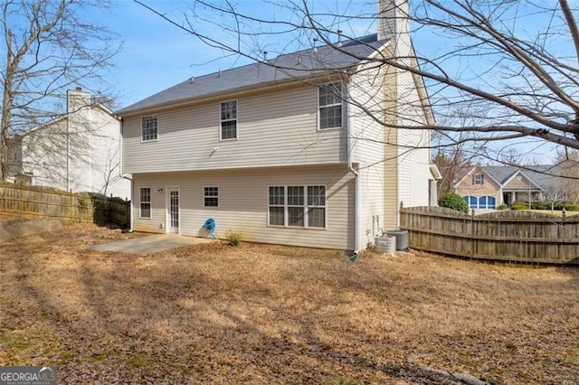 rear view of house with a fenced backyard, a patio, a chimney, and central AC unit