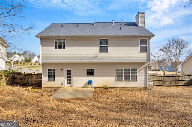 back of house with a patio, a chimney, a fenced backyard, and a lawn