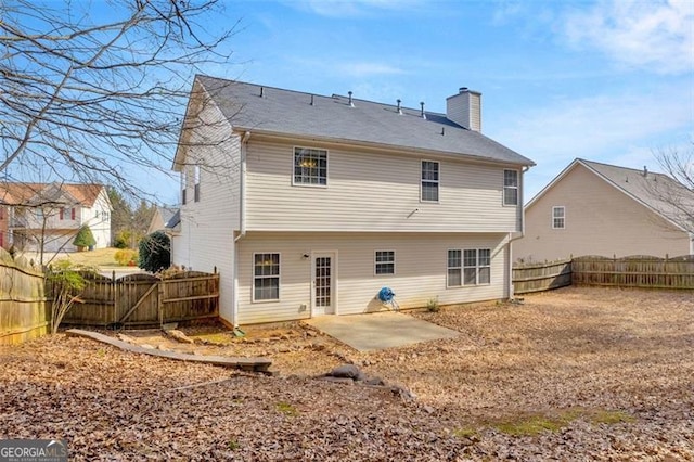 rear view of property with a fenced backyard, a patio, and a chimney