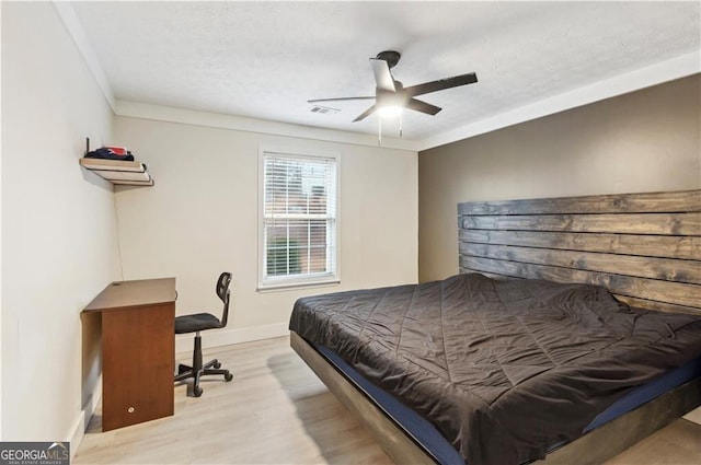 bedroom featuring a ceiling fan, visible vents, baseboards, light wood finished floors, and crown molding