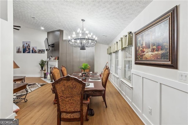 dining room with a notable chandelier, a textured ceiling, and light wood-style floors