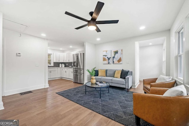 living area featuring attic access, visible vents, baseboards, light wood-type flooring, and recessed lighting