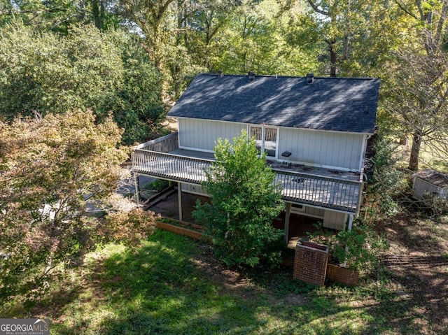 back of property with roof with shingles and a wooden deck