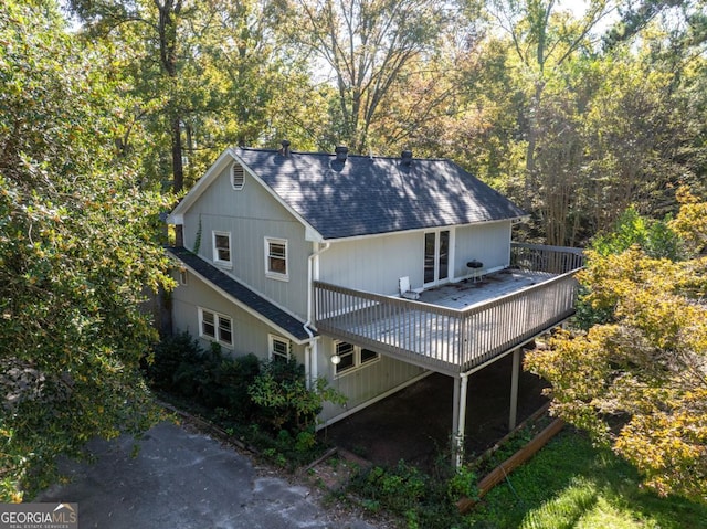 exterior space with a shingled roof and a wooden deck