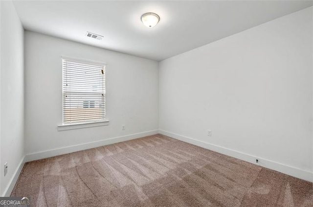 spare room with carpet flooring, visible vents, and baseboards