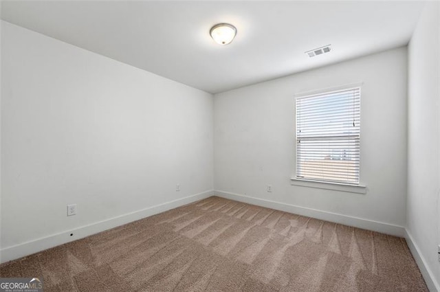 carpeted spare room featuring visible vents and baseboards