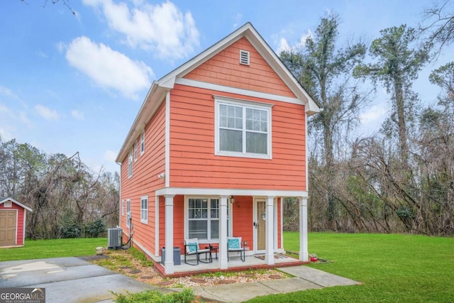 traditional-style home with a storage shed, a front yard, central AC unit, and an outbuilding