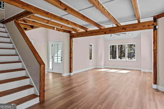 unfurnished living room featuring vaulted ceiling with beams, stairs, light wood-style flooring, and baseboards