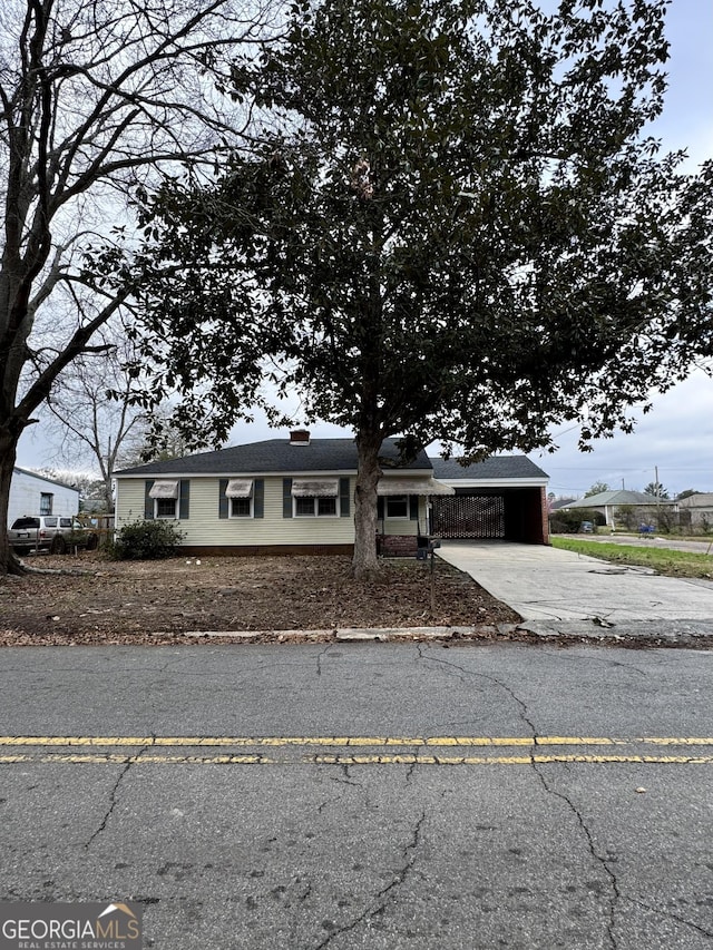 view of front of house with concrete driveway and an attached carport