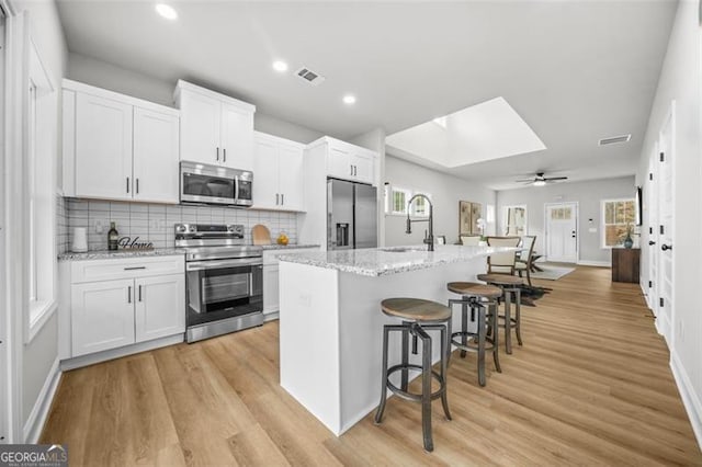 395 Lake Ave, Atlanta, GA 30318 - kitchen featuring visible vents, light wood finished floors, a kitchen breakfast bar, and stainless steel appliances