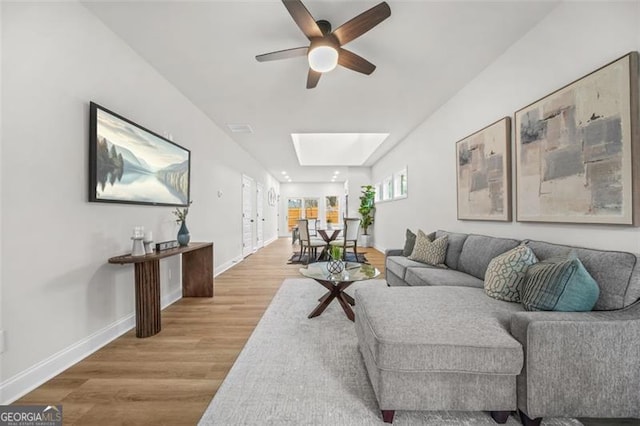 395 Lake Ave, Atlanta, GA 30318 - living room featuring baseboards, a ceiling fan, light wood finished floors, and a skylight