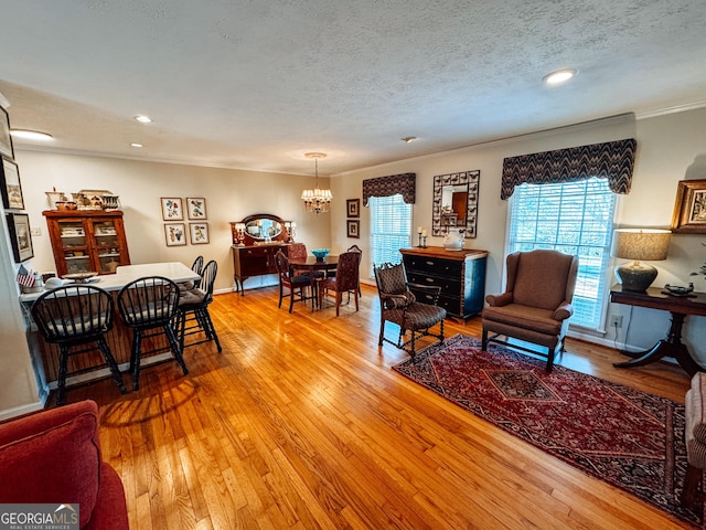 living area featuring baseboards, hardwood / wood-style flooring, an inviting chandelier, crown molding, and a textured ceiling