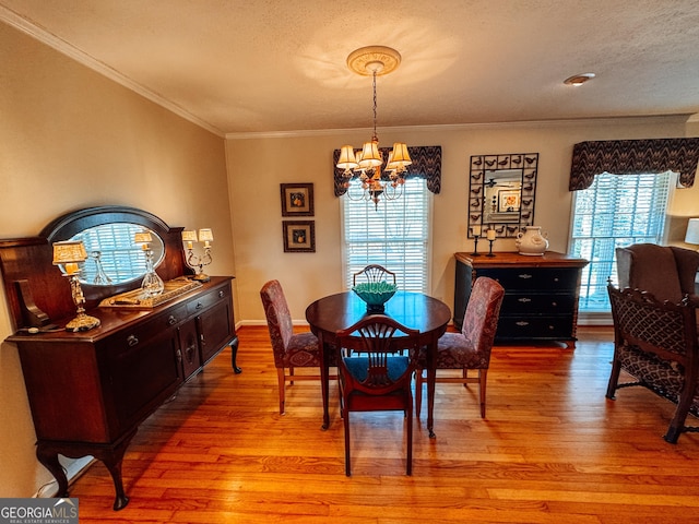 dining space featuring a chandelier, light wood-type flooring, ornamental molding, and a textured ceiling