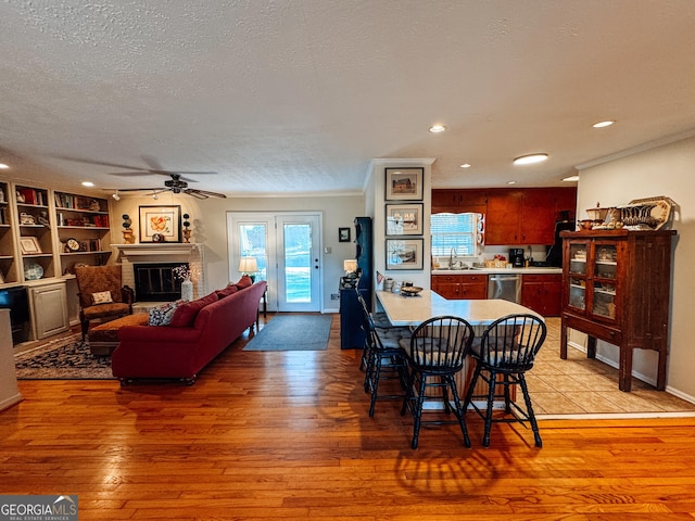 dining space featuring light wood finished floors, a brick fireplace, and a textured ceiling