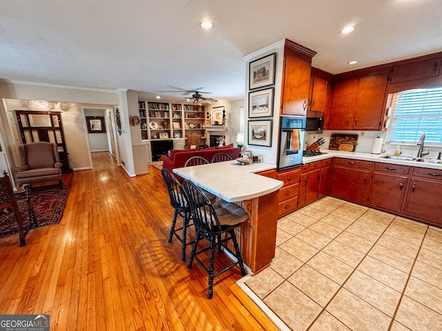 kitchen featuring appliances with stainless steel finishes, open floor plan, a peninsula, a fireplace, and a sink