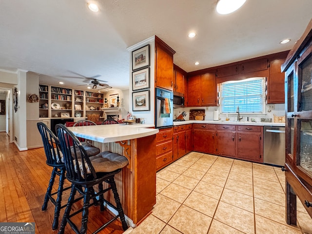 kitchen with stainless steel appliances, light countertops, a ceiling fan, a sink, and a peninsula