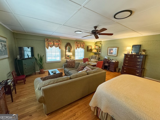 bedroom featuring ceiling fan, brick wall, and wood finished floors