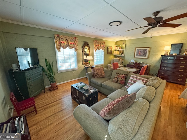 living room featuring brick wall, baseboards, ceiling fan, and wood finished floors