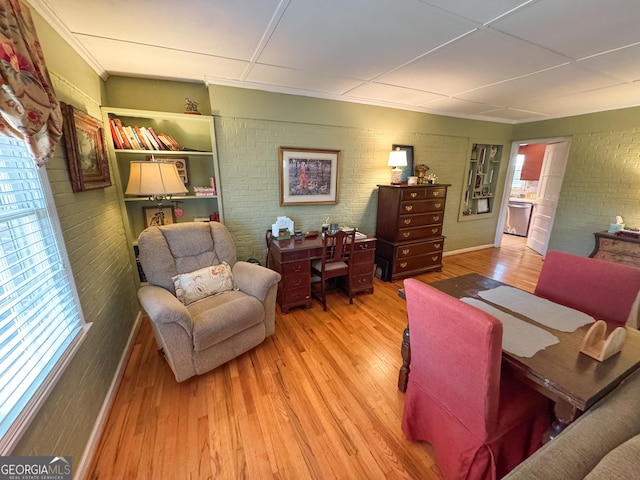 living area with brick wall and wood finished floors