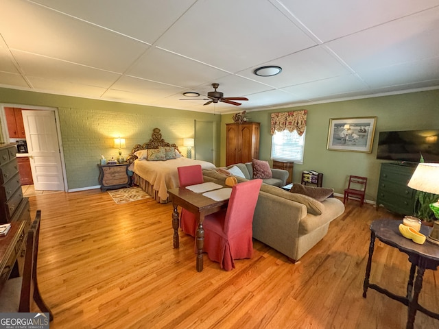 bedroom with a ceiling fan, baseboards, light wood-style flooring, and brick wall