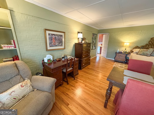 office space with ornamental molding, brick wall, and light wood finished floors