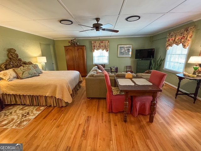 bedroom featuring ornamental molding, multiple windows, and light wood-style flooring