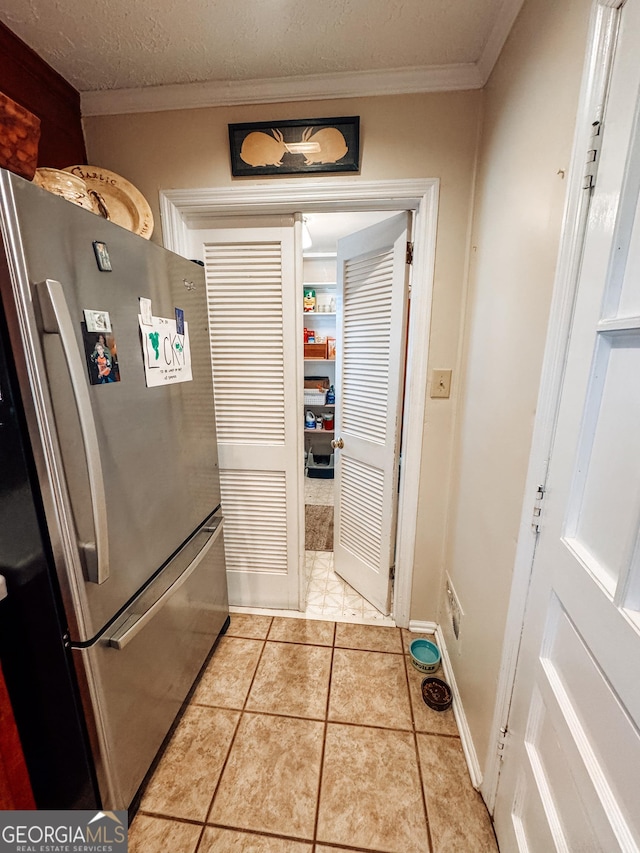 interior space with ornamental molding, a textured ceiling, and light tile patterned floors