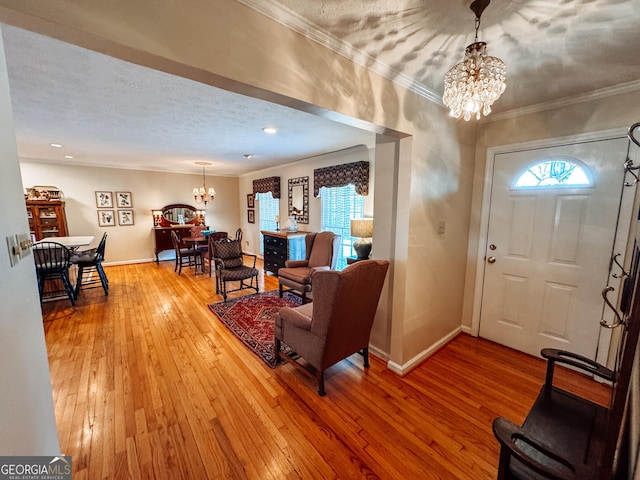 foyer featuring baseboards, ornamental molding, wood-type flooring, and a notable chandelier