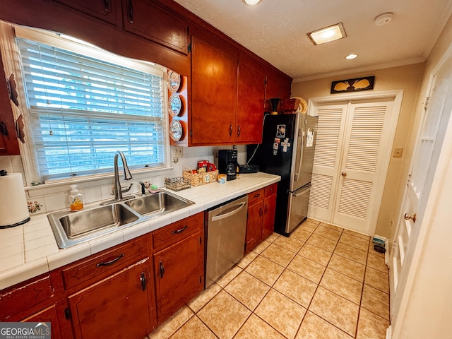 kitchen with tile countertops, stainless steel appliances, light tile patterned floors, and a sink