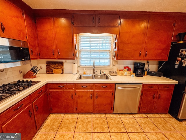 kitchen featuring light tile patterned floors, appliances with stainless steel finishes, a sink, and decorative backsplash