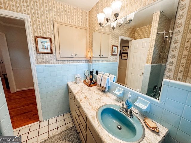 bathroom featuring a shower, a wainscoted wall, vanity, and wallpapered walls