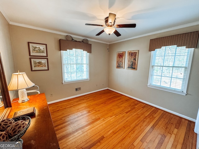 unfurnished room with light wood-style floors, a wealth of natural light, crown molding, and baseboards