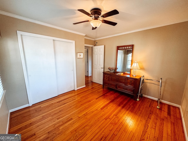 bedroom featuring a ceiling fan, baseboards, ornamental molding, a closet, and light wood finished floors