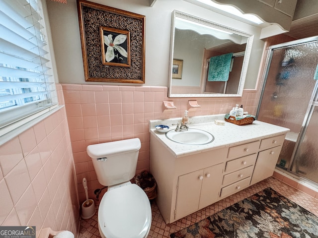 full bath with toilet, a wainscoted wall, vanity, tile walls, and a shower stall