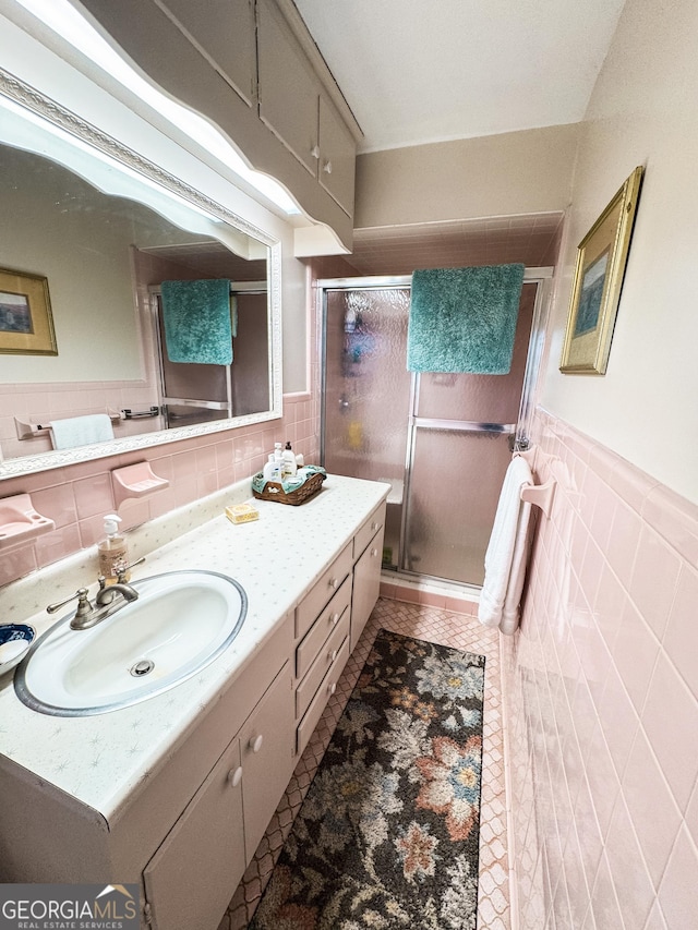 full bathroom with a stall shower, a wainscoted wall, tile patterned flooring, vanity, and tile walls