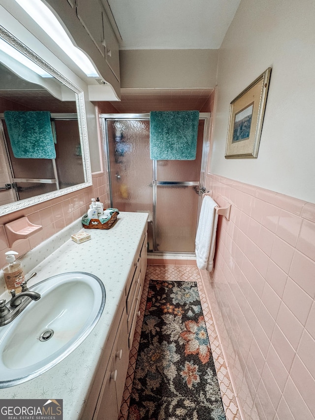 full bath with vanity, a shower stall, and tile walls