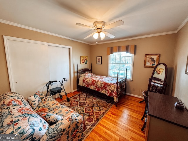 bedroom with baseboards, a ceiling fan, ornamental molding, light wood-type flooring, and a closet