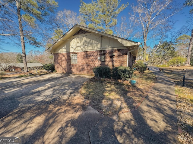 view of side of home featuring brick siding and driveway