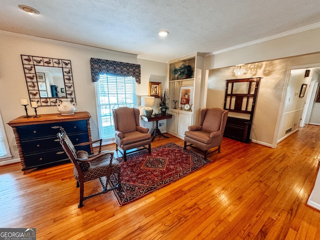 sitting room featuring wood-type flooring, crown molding, a textured ceiling, and baseboards