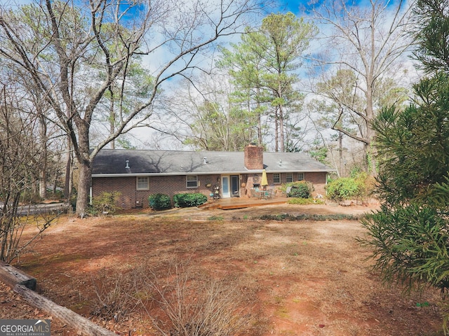 rear view of property featuring brick siding and a chimney