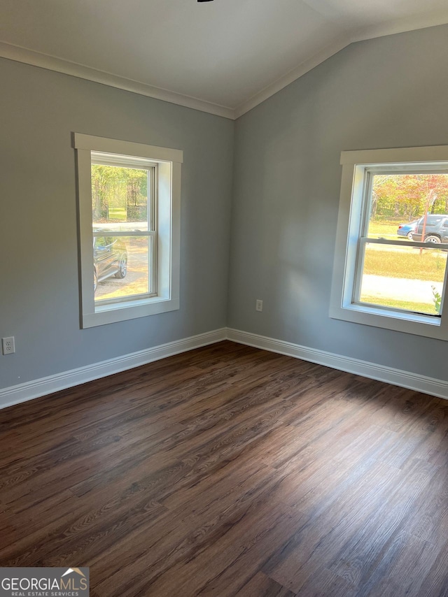 spare room with vaulted ceiling, ornamental molding, dark wood-style flooring, and baseboards