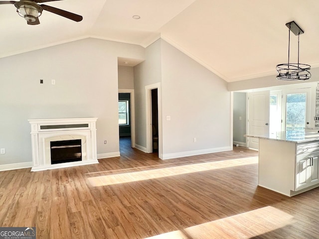 unfurnished living room with vaulted ceiling, a fireplace, baseboards, and light wood-style floors