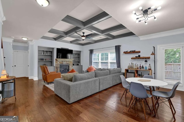 living room with beam ceiling, coffered ceiling, dark wood finished floors, and a stone fireplace