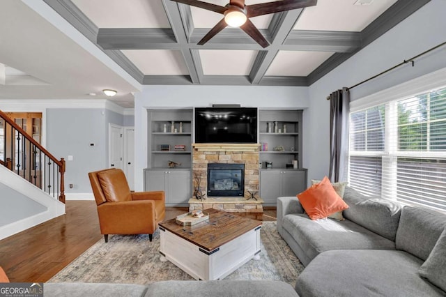 living area featuring a fireplace, light wood-type flooring, coffered ceiling, baseboards, and stairs