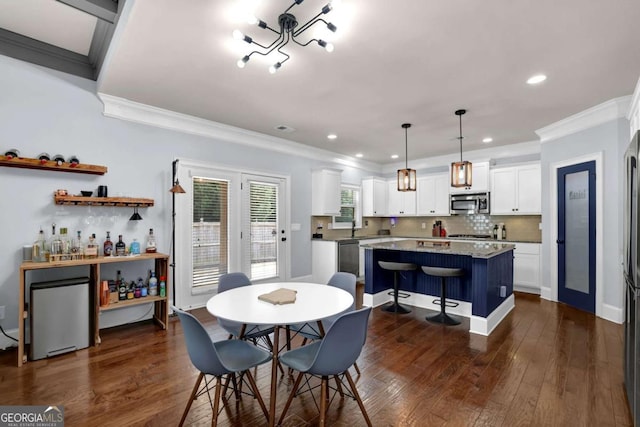 dining space with dark wood-style floors, crown molding, and recessed lighting